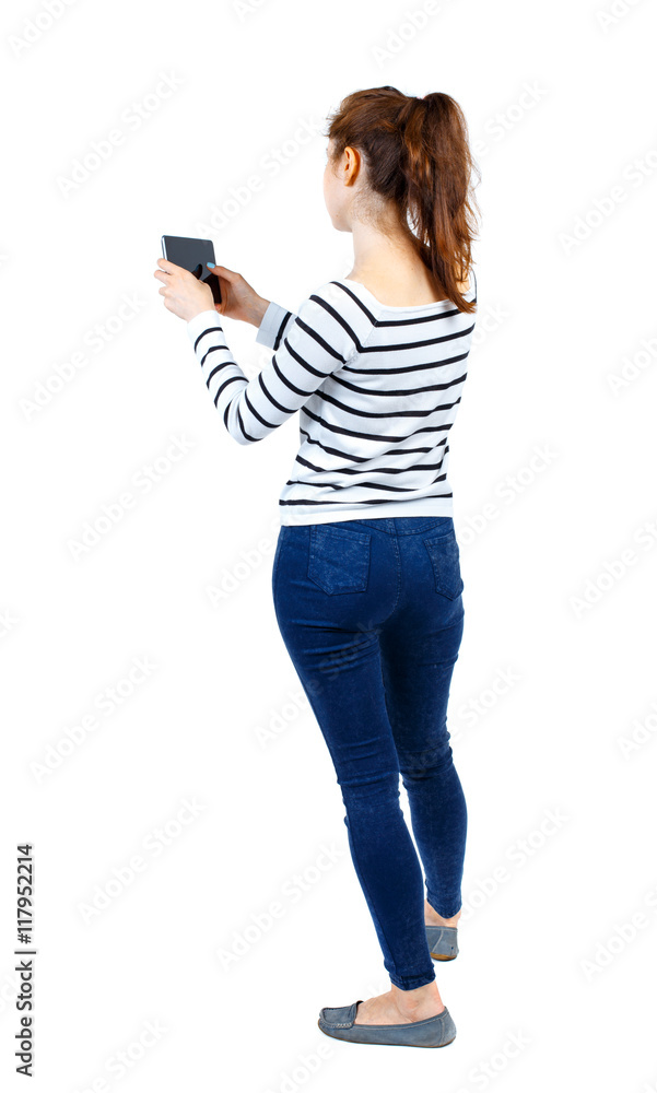 back view of standing young beautiful woman using a mobile phone. girl watching. Rear view people collection. backside view of person. Isolated over white background. Girl in a striped sweater back view of standing young beautiful woman using a mobile phone. girl watching. Rear view people collection. backside view of person. Isolated over white background. Girl in a striped sweater