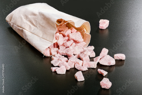 cherry flavored sugar chunks in bag on black  background photo