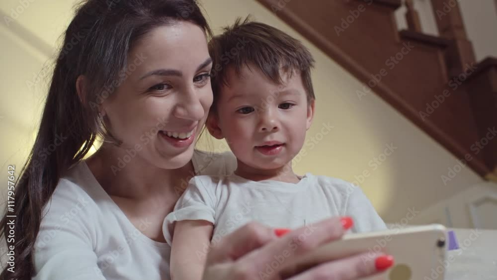 Mom and cute little son smiling and laughing while taking selfie with smart phone Mom and cute little son smiling and laughing while taking selfie with smart phone