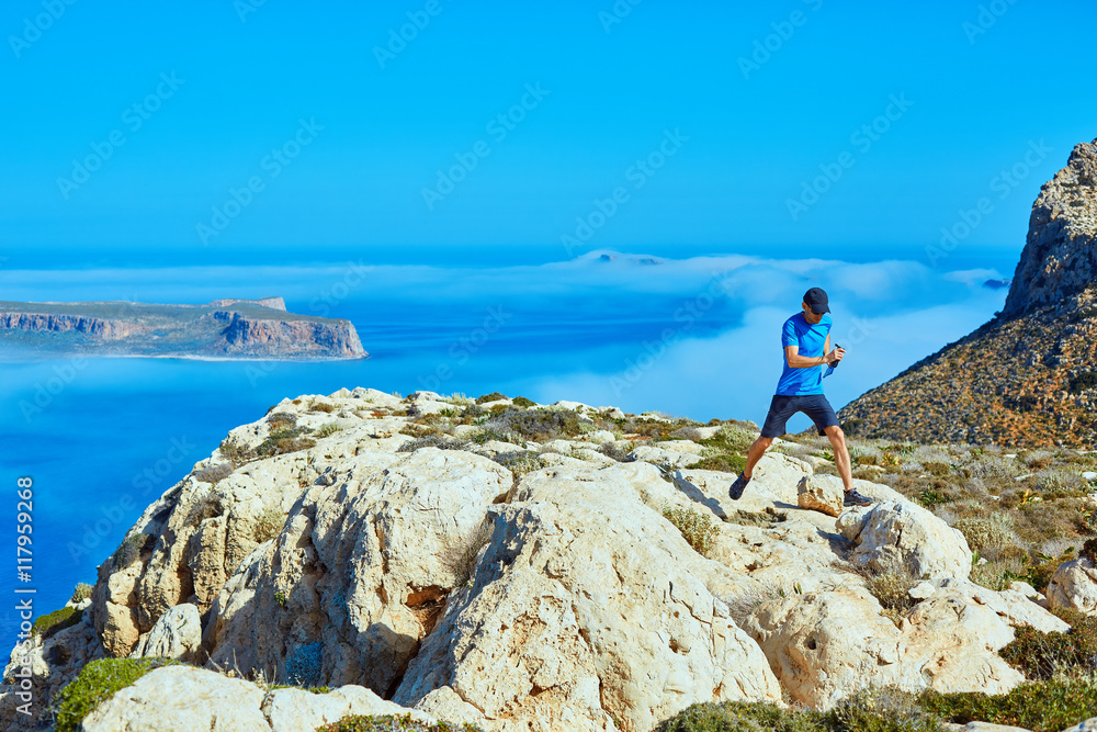 man runs on a cliff against a blue sea