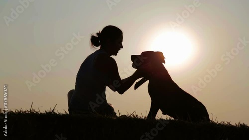 Silhouette of a young girl with a dog in the manger.
