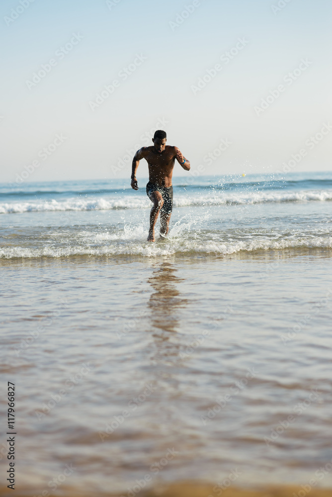 Man training at the beach. Black athlete running into the sea for leg power training. Man training at the beach. Black athlete running into the sea for leg power training.