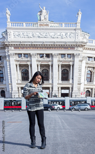 Asian woman studying a map on the square near the theater