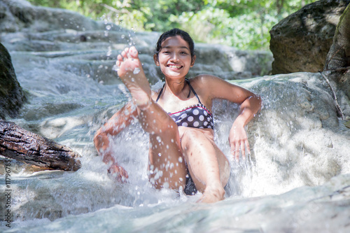 woman in retro swimsuit playful in a waterfall