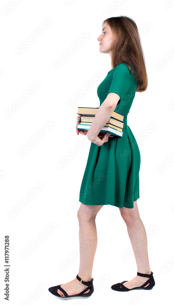 Girl comes with stack of books. side view. Rear view people collection. backside view of person. Isolated over white background. The slender brunette in a green short dress is in the side with a Girl comes with stack of books. side view. Rear view people collection. backside view of person. Isolated over white background. The slender brunette in a green short dress is in the side with a