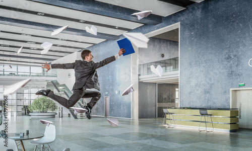 Jumping businessman in office . Mixed media
