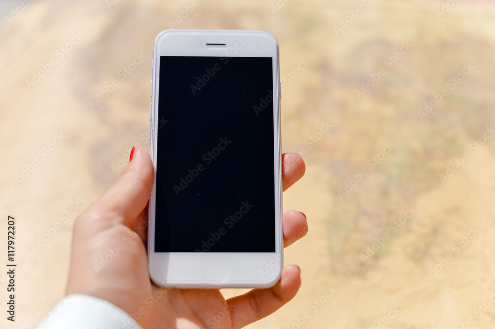 Person using mobile phone above global map background, closeup top view, flat lay mockup style
