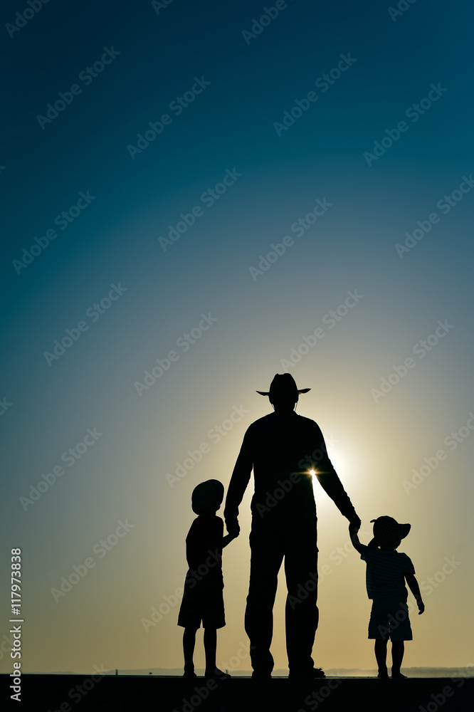 Beautiful sunset silhouette of father with kids, outdoors background