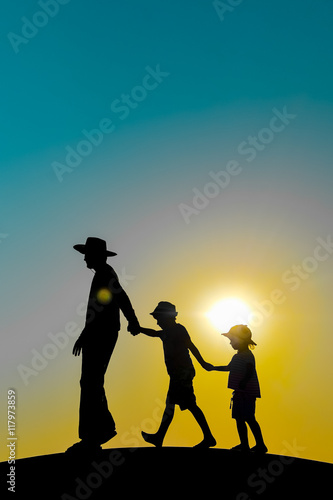 Beautiful sunset silhouette of father with kids  outdoors background