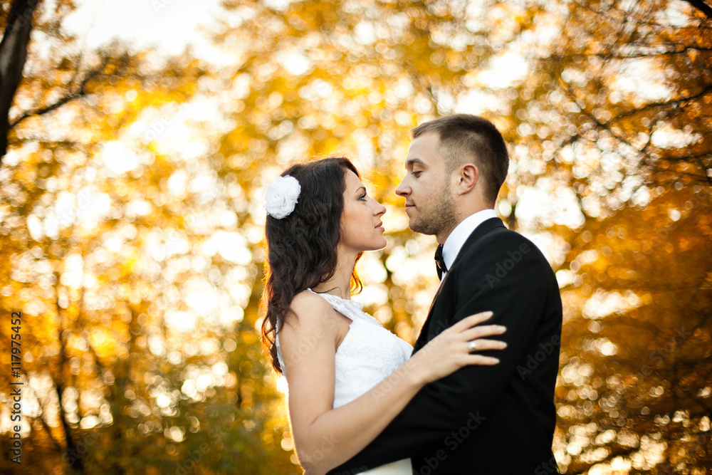Groom looks at a bide seriously standing in the autumn park Groom looks at a bide seriously standing in the autumn park