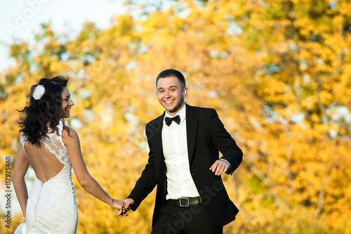 Merry newlyweds dance in the golden forest