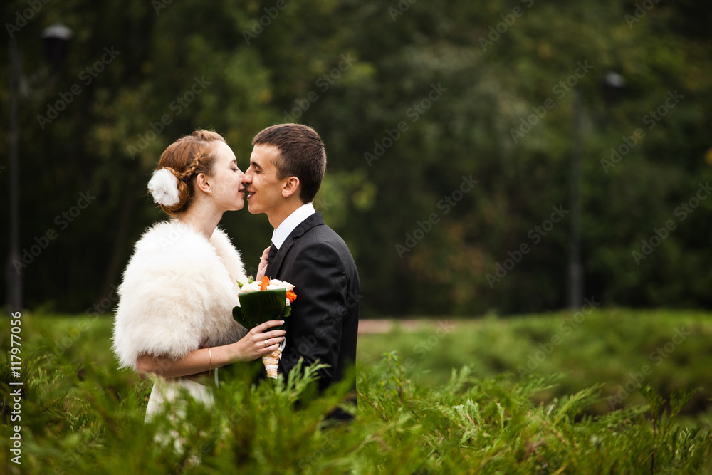 Groom smiles kissing a bride with flowers in her hair Groom smiles kissing a bride with flowers in her hair