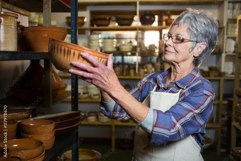 Female potter placing bowl on shelf Female potter placing bowl on shelf