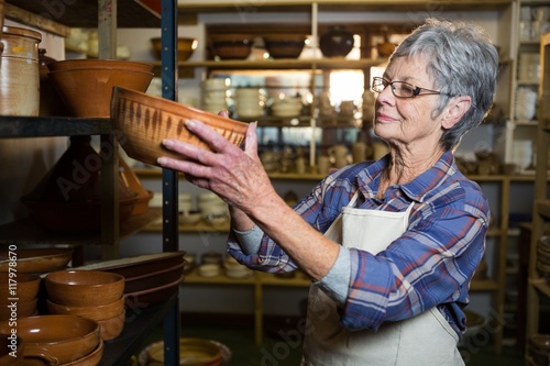 Female potter placing bowl on shelf