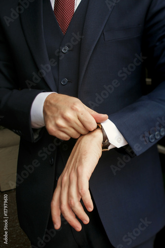 Man in black suit puts his sleeve over a watch