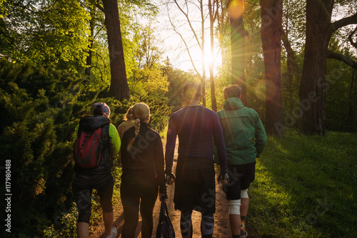 Group of friends walking with backpacks in sunset from back. Adventure, travel, tourism, hike and people friendship concept.