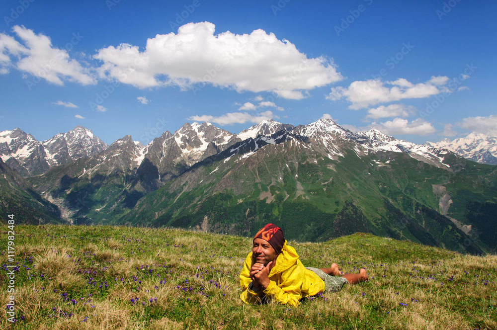 man lying down resting on grass background of snow-capped peaks the mountains Georgia