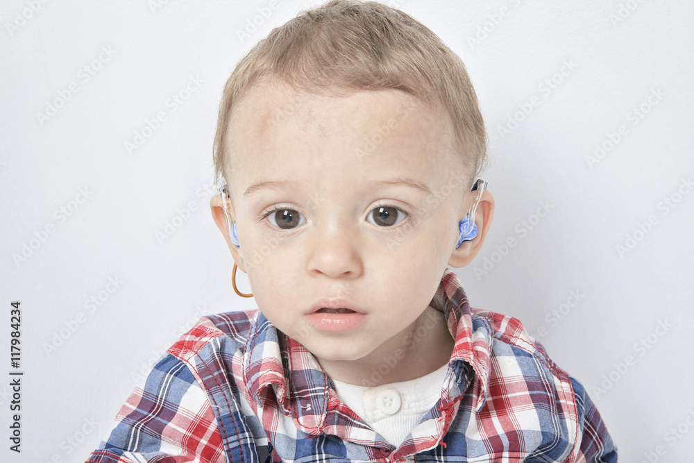 A boy with a hearing aids on gray background A boy with a hearing aids on gray background