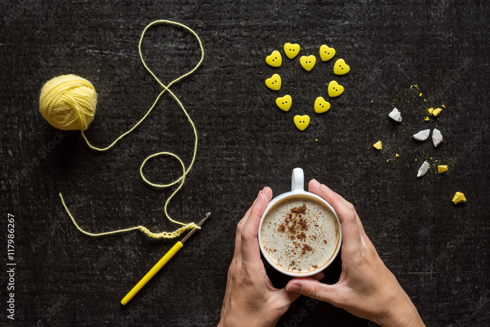 Crocheting, button heart and hands with coffee