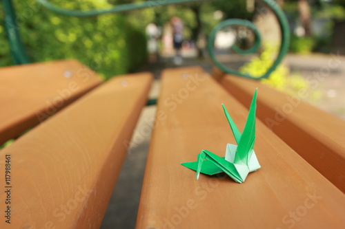 Paper crane resting on wooden bench