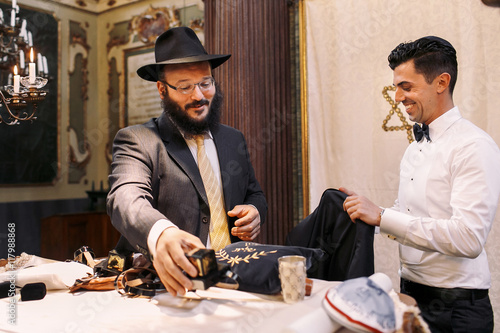 Smiling Jew prepares groom for a wedding photo