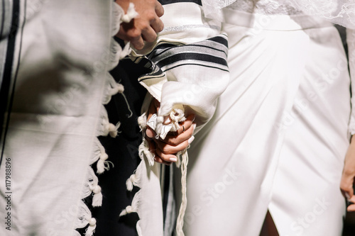 Closeup of Jewish groom holding bride's hand photo