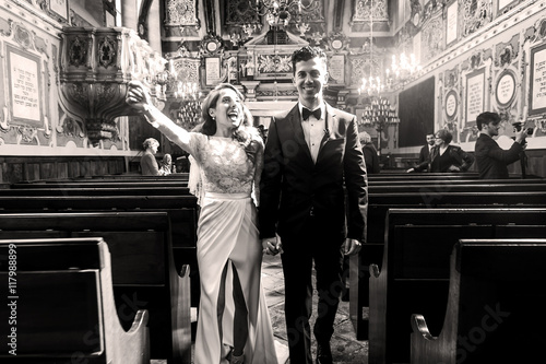 Happy bride spreads her hands walking with a groom out of synago photo