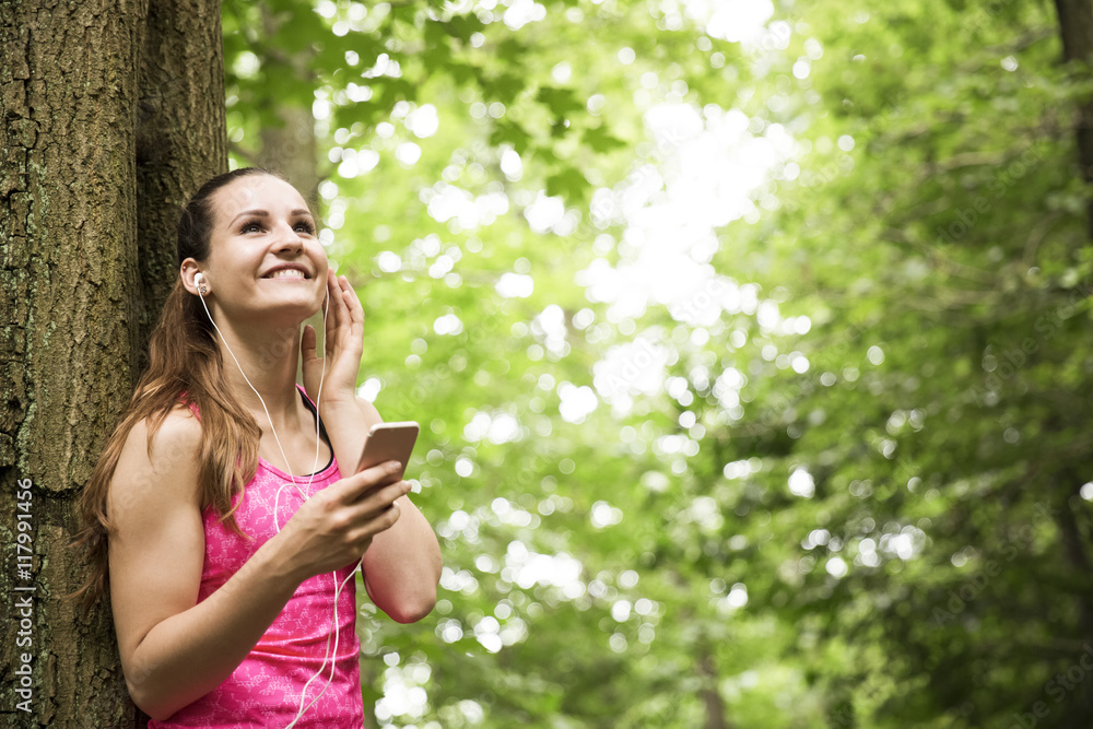 Sportive young woman with smartphone and earbuds Sportive young woman with smartphone and earbuds