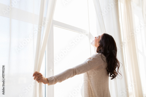 close up of pregnant woman opening window curtains photo