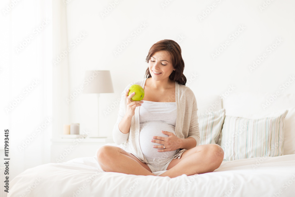 happy pregnant woman eating green apple at home happy pregnant woman eating green apple at home