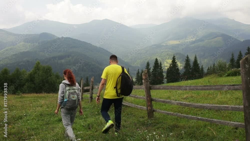 Couple Backpackers hiking on the path in mountains Couple Backpackers hiking on the path in mountains