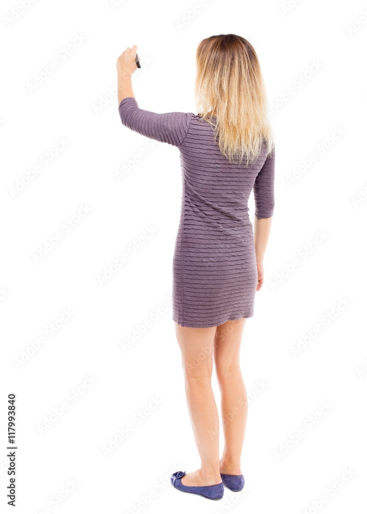 back view of writing beautiful woman. Young girl in dress. Rear view people collection. backside view of person. Isolated over white background. The girl in the purple dress draws a felt-tip pen on back view of writing beautiful woman. Young girl in dress. Rear view people collection. backside view of person. Isolated over white background. The girl in the purple dress draws a felt-tip pen on