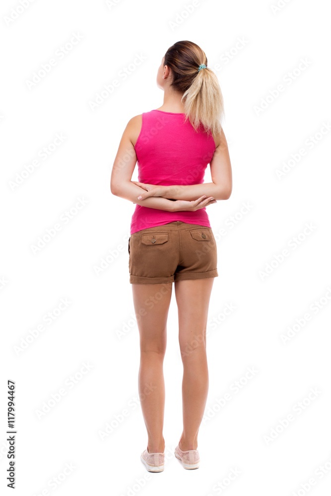 back view of standing young beautiful  woman.  girl  watching. Rear view people collection.  backside view of person.  Isolated over white background. Blonde in brown shorts stands with his hands