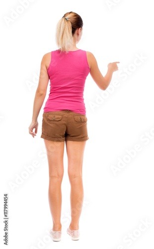 back view of young woman presses down on something. Isolated over white background. Rear view people collection. backside view of person. The girl in brown shorts and a pink tank top is pointing to