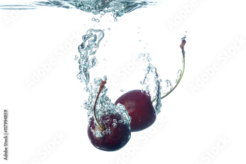 Cherries splashing into water on white background