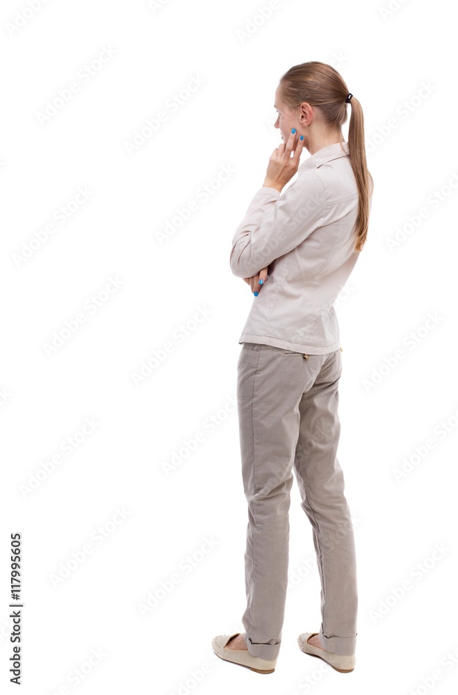 back view of standing young beautiful woman. girl watching. Rear view  people collection. backside view of person. Girl with long hair in a white  jacket standing sideways resting his chin. Stock Photo