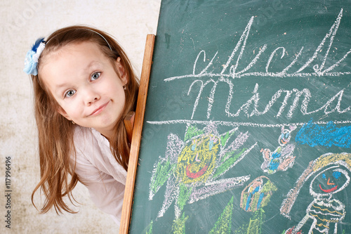 Young girl drawing and writing with chalk on the blackboard photo