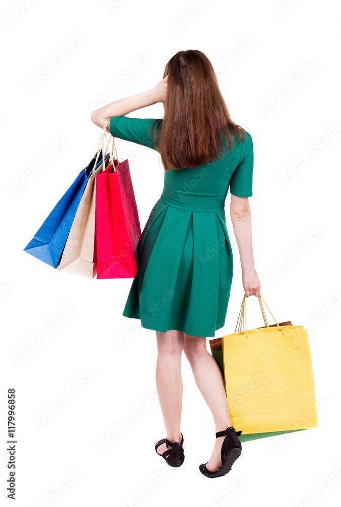 back view of woman with shopping bags . beautiful brunette girl in motion.  backside view of person.  Rear view people collection. Isolated over white background. Girl in green short dress is looking