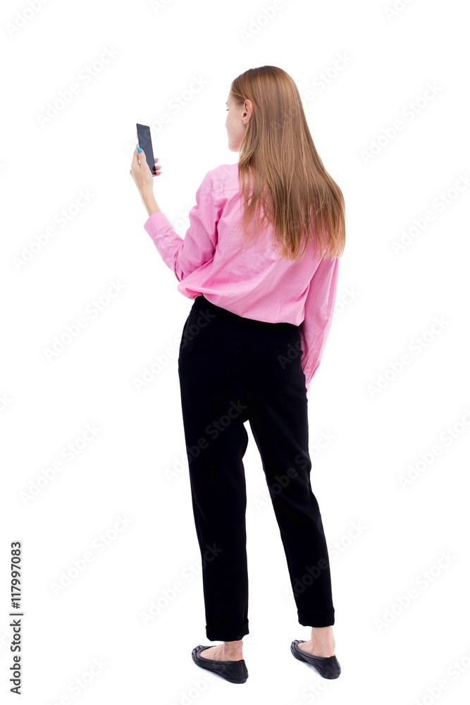 back view of standing young beautiful woman and using a mobile phone. girl watching. Rear view people collection. backside view of person. Isolated over white background. The girl office worker back view of standing young beautiful woman and using a mobile phone. girl watching. Rear view people collection. backside view of person. Isolated over white background. The girl office worker
