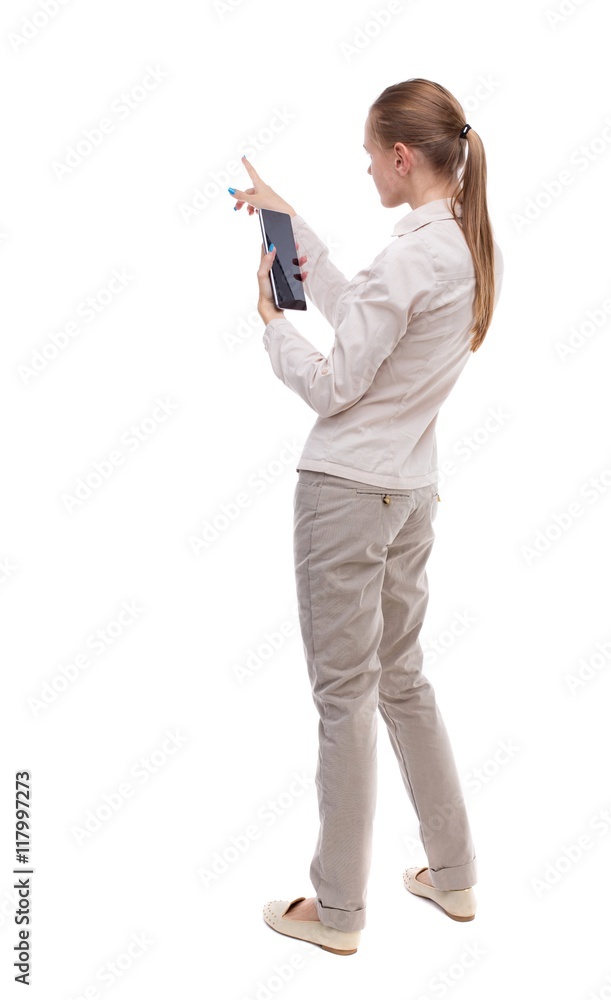 back view of standing young beautiful girl with tablet computer in the hands of. girl watching. Rear view people collection. backside view of person. Isolated over white background. A girl in a back view of standing young beautiful girl with tablet computer in the hands of. girl watching. Rear view people collection. backside view of person. Isolated over white background. A girl in a