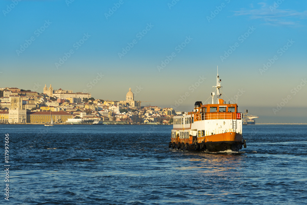 Passenger boat (Cacilheiro) crossing the Tagus River with the Lisbon skyline as background; Concept for travel in Lisbon, Portugal