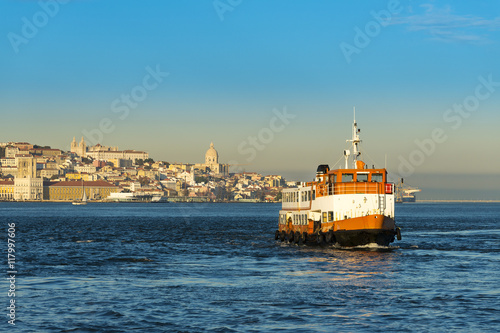 Passenger boat (Cacilheiro) crossing the Tagus River with the Lisbon skyline as background  Concept for travel in Lisbon, Portugal © Tiago Fernandez