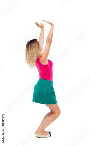 back view of woman pushes wall. Isolated over white background. Rear view people collection. backside view of person.The blonde in a green skirt and pink blouse sitting down holding something heavy