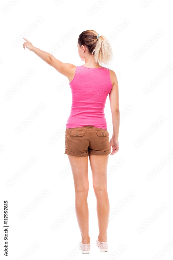 Back view of pointing woman. beautiful girl. Rear view people collection. backside view of person. Isolated over white background. The girl in brown shorts and a pink tank top is pointing to the Back view of pointing woman. beautiful girl. Rear view people collection. backside view of person. Isolated over white background. The girl in brown shorts and a pink tank top is pointing to the