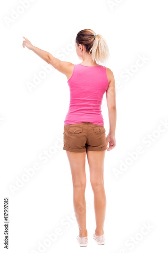 Back view of pointing woman. beautiful girl. Rear view people collection. backside view of person. Isolated over white background. The girl in brown shorts and a pink tank top is pointing to the