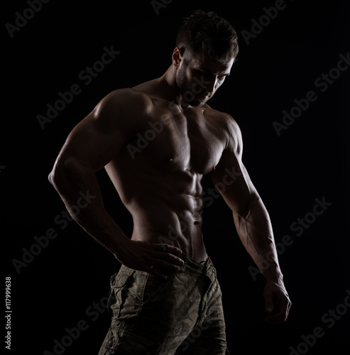 Muscular athlete bodybuilder man on a dark background © bondarchik