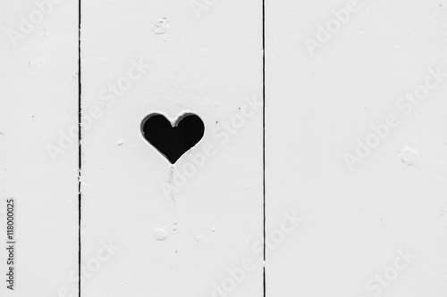 Heart shaped hole in white wooden wall