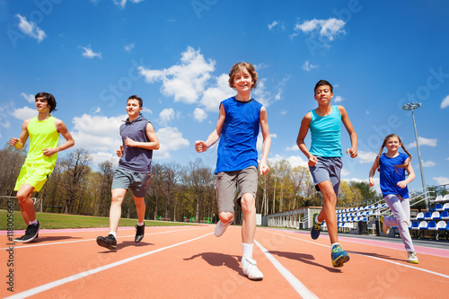 Five happy teenage kids running on the stadium