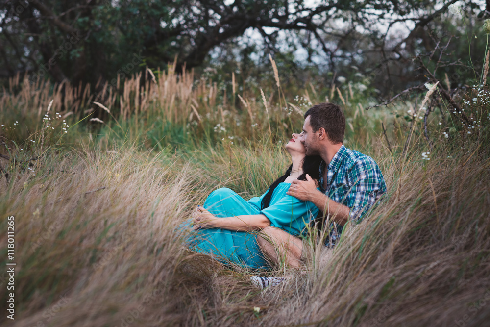 Shot of young man and woman sitting together outdoors on grass field. Romantic young couple in meadow,love,relatonships,lifestyle Shot of young man and woman sitting together outdoors on grass field. Romantic young couple in meadow,love,relatonships,lifestyle