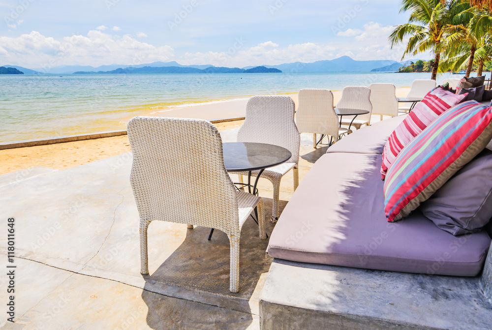 Sofa seats and pillows with chairs in front of the beach